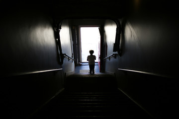 Silhouette of a Little Boy Walking Down a Dark Staircase