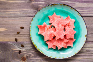 Pieces of watermelon in the form of stars on a ceramic plate on a wooden table. Top view