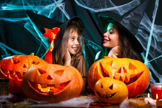 Happy Halloween. Mother and her daughter in witch costumes having fun at home.