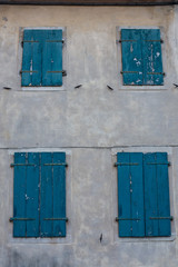 Quattro finestre chiuse color smeraldo su una parete grigia anticata
