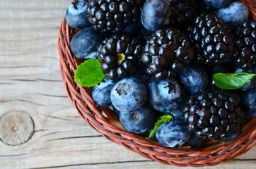 Freshly picked organic blackberries and blueberries in a basket on old wooden table.Healthy eating,vegan food or diet concept.Selective focus.