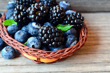 Fresh ripe organic blackberries and blueberries in a basket on old wooden table.Healthy eating,vegan food or diet concept.Selective focus.
