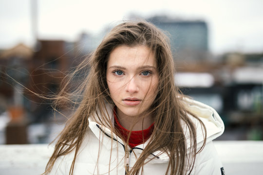 Portrait of blond young woman with blue eyes standing outdoors
