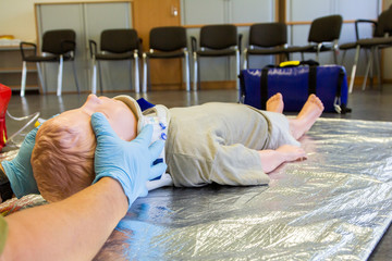 Human hands stabilisations the neck from a medical training puppet for ambulance man