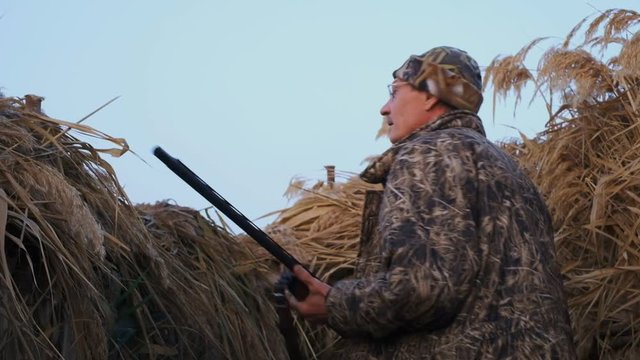 Amateur hunting in the fall for ducks. Autumn duck hunting on a foggy morning lake .. A foggy morning on the lake, a hunter hunts down game. In the hunting box of reeds, he hides.