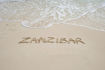zanzibar script on light sand and ocean wave