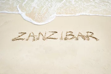 Fotobehang zanzibar script on light sand and ocean wave © stockmaliavanne