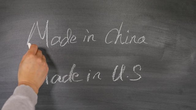 Female hand crossing out and erasing made in China writing on chalkboard for trade war concept 