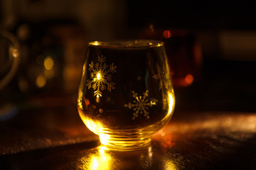Glass candle holder with Christmas Christmas graphics in the form of the glass. Snowflakes, Christmas trees glow in the decorative candlestick inside yellow light. Festive Christmas decor.