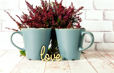 Ceramic cups and wooden inscription  love  on white wooden background with heather, close up,copy space