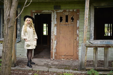 The beautiful girl with long curly hair in a black hat in an abandoned house