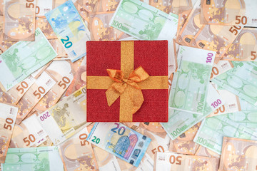A red gift on a banknote background. Top view.