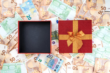 An open red gift on a banknote background. Top view