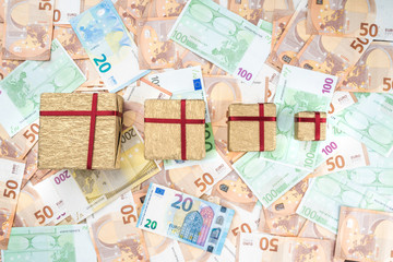 Gifts of different sizes on a background of different value banknotes. Top view.