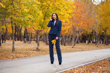Fototapeta premium Happy arab businesswoman in blue suit walking in autumn park