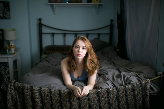 Portrait of blond young woman lying on bed at home