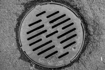 Manhole cover in the road of asphalt