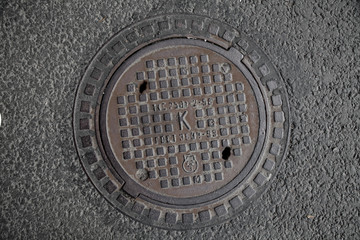 Manhole cover in the road of asphalt