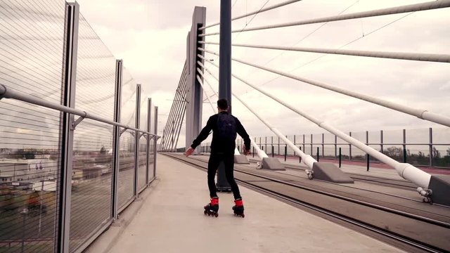 Young man in rollerblades doing spin in the city, super slow motion 

