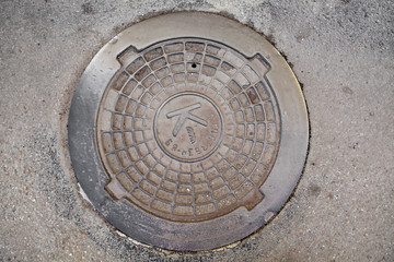 Manhole cover in the road of asphalt