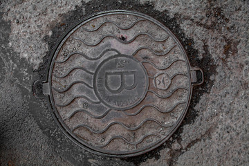 Manhole cover in the road of asphalt