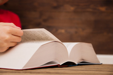 Close-up of the hand on the book is going to turn the page to the next chapter. girl leafing through the pages of the book. a girl with a book