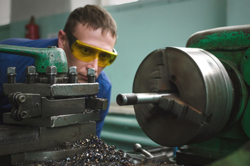 Turner worker is working on a lathe machine in a factory.