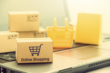 Shop online, ecommerce / retail commerce concept : Box with shopping cart and words online shopping, shopping basket, shopping bag on a laptop computer, depicts customers buy products via online store