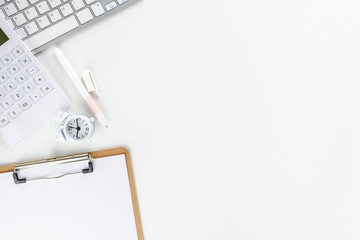Top or above view / flat lay of office supply on desk table, business / personal work space, calculator, keyboard, pen, clock, blank paper on a clipboard, empty space for text or schedule. White theme