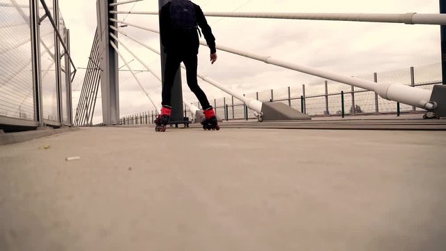 Young man in rollerblades doing spin in the city,  focus on legs super slow motion 
