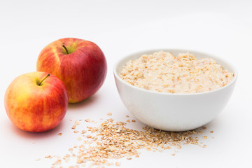 Oatmeal in white bowl and red apple on white background. Isolated on white. Healthy food