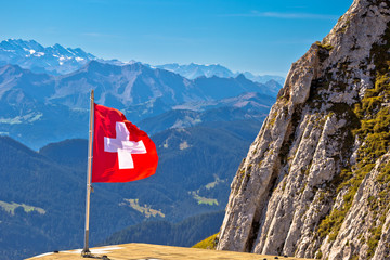 Swiss flag on Pilatus mountain with background alpine peaks