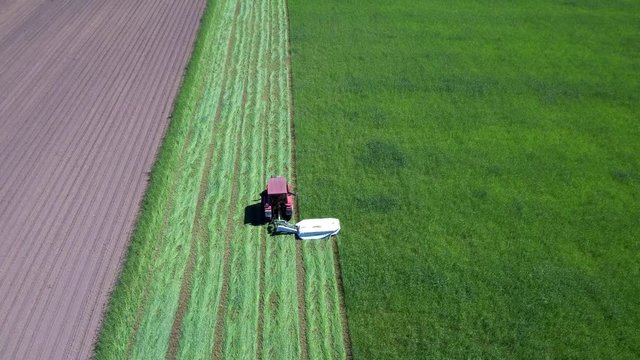 Mężczyzna w traktorze koszący latem trawę na łące IV