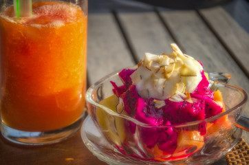 Tropical fruit smoothie and exotic fresh fruit with yogurt in a glass bowel on a rustic table