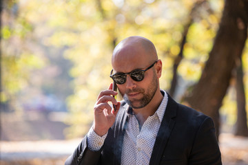 A handsome young businessman talking on his phone in the park