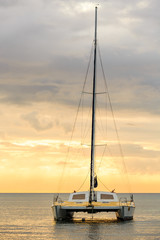 Catamaran glides at twilight on water surface of the baltic sea. Sailing into the golden sun