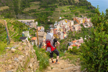 Young father carrying his child in baby carrier while exploring coastal town.