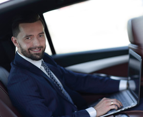 Close-up of a businessman with a laptop sitting in the car