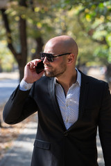 A handsome young businessman talking on his phone in the park