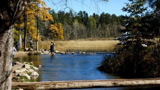 Lake Itasca held behind a man made dam at the headwaters of the Mississippi River at Lake Itasca State Park in Minnesota. Tourists take pictures by the rocks.