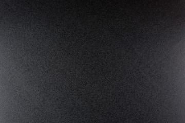 Black, rough textured background lit with dim light.