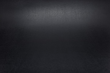 Black, rough textured background lit with dim light.