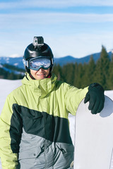 Fototapeta na wymiar Snowboarder with action camera on a helmet. Close up Portrait of snowboarder in Carpathian Mountains, Bukovel Snowboarder. A mountain range reflected in the ski mask. wearing ski glasses