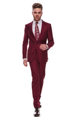 confident man with beard walking while wearing grena suit