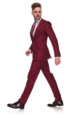 side view of confident businessman walking and looking behind