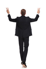 back view of stepping businessman celebrating and making victory sign
