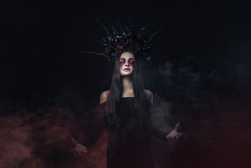 Terrible horror Halloween Vampire Woman portrait. Beauty Vampire Witch lady with blood on mouth posing in deep forest. Fashion Art design. holds a candle in his hands and reads curses