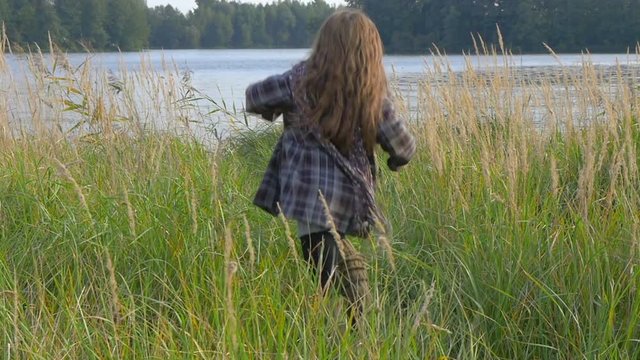 girl in coat igret in the park on the banks of the river, running and having fun