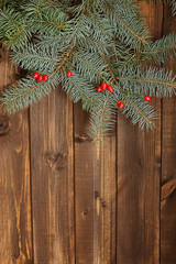 Christmas tree branches green with red berries on a wooden background boards