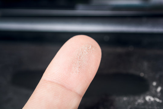 Macro Of A Finger Streaked Through Dust On A Black Surface